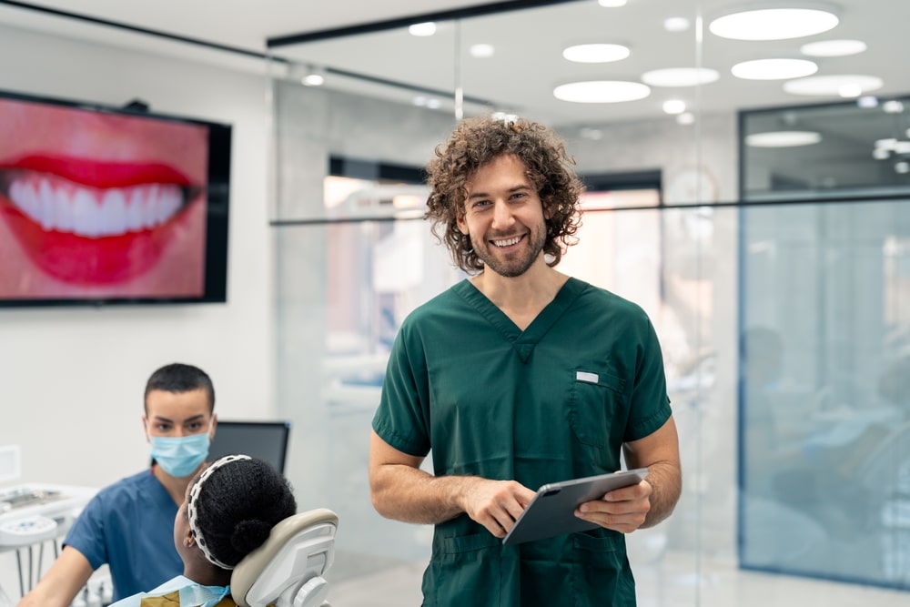 Proud,Young,Dental,Surgeon,Wearing,Green,Medical,Uniform,Holding,Digital