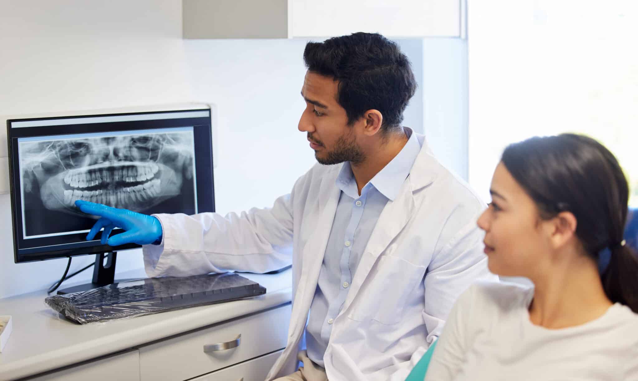Dentist, consulting and x ray of teeth on computer for patient education, dental diagnosis and treatment planning. Oral assessment, person and screen with mouth scan for hygiene, health and wellness